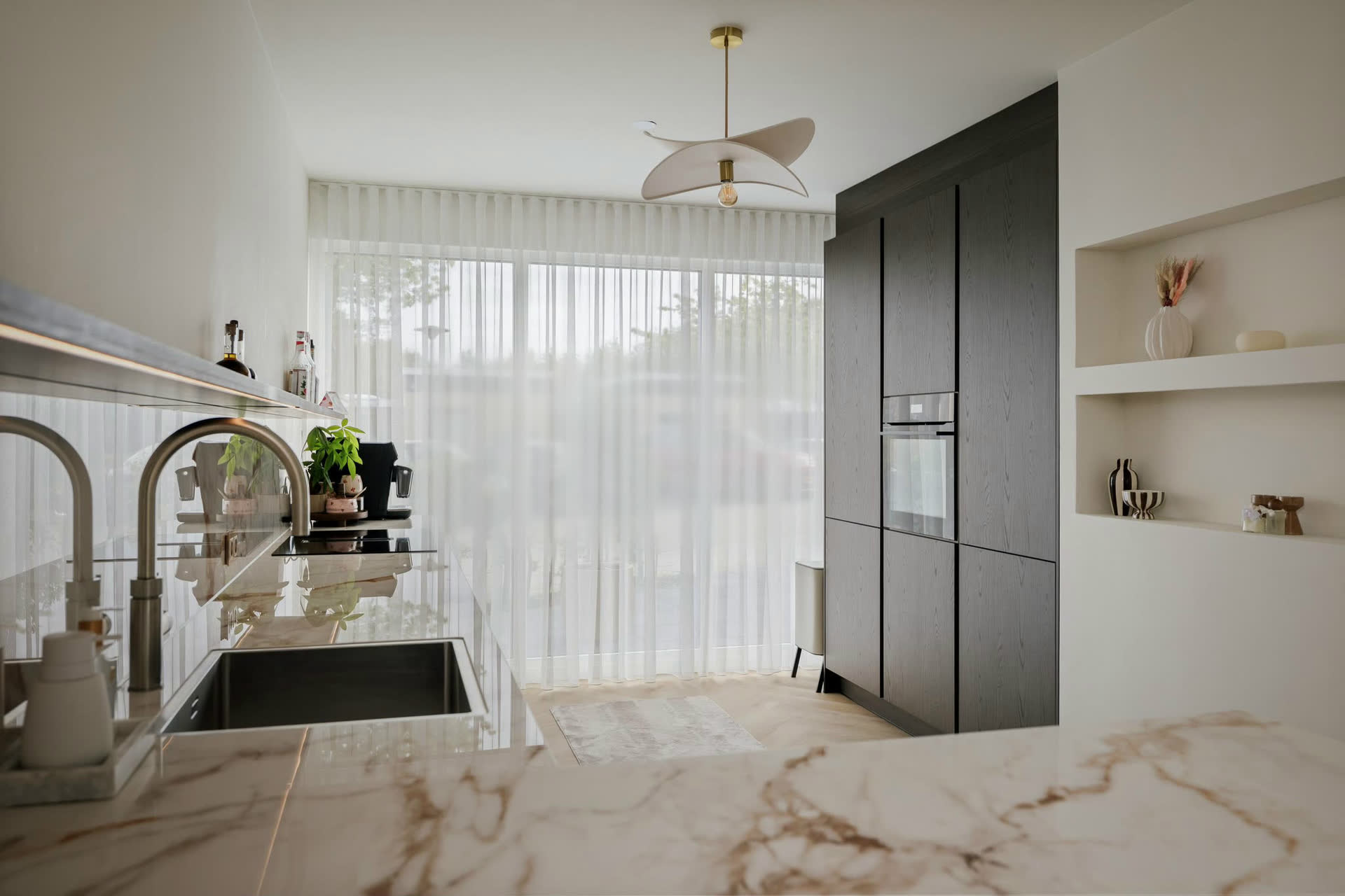 Een keuken die wij plaatsten in Deventer: hoge kastenwand in donker fineer met inbouwoven, een licht werkblad in marmerlook met kokendwaterkraan en open nissen in de wand.
