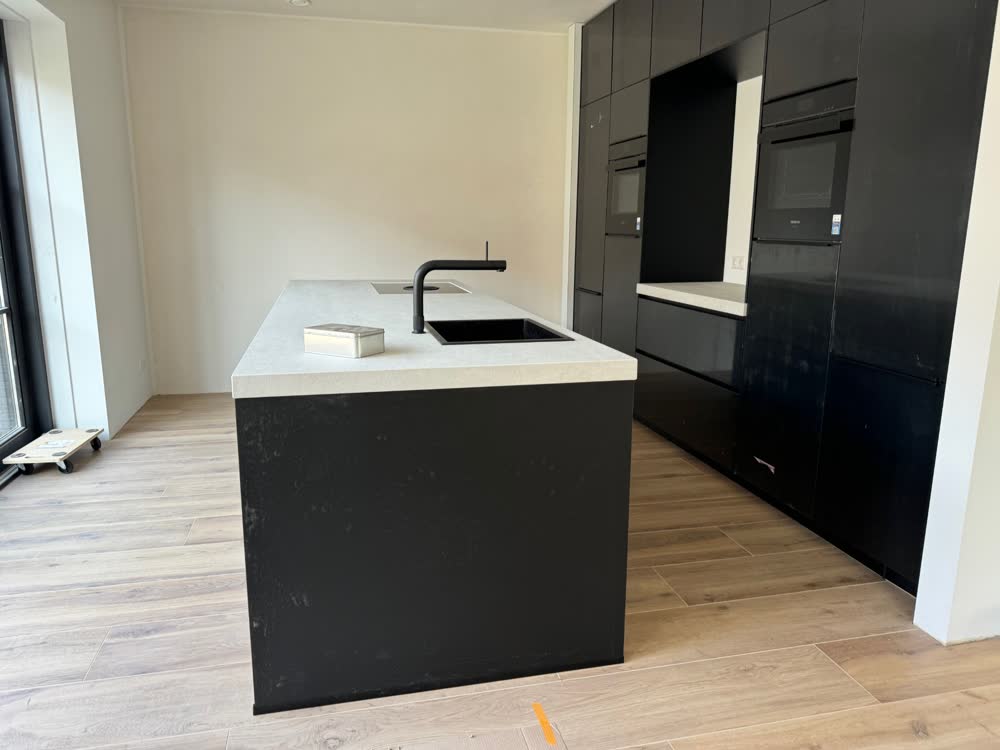 Zwarte keuken met kookeiland en wit blad