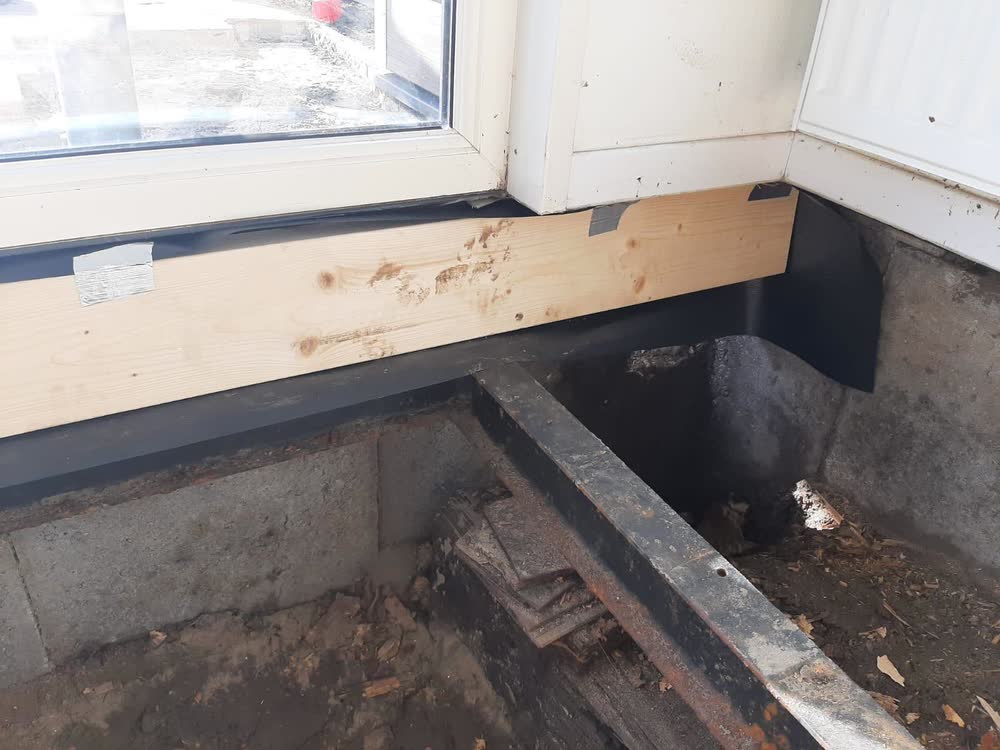 De nieuwe balk onder de pui met zwarte folie langs de fundering