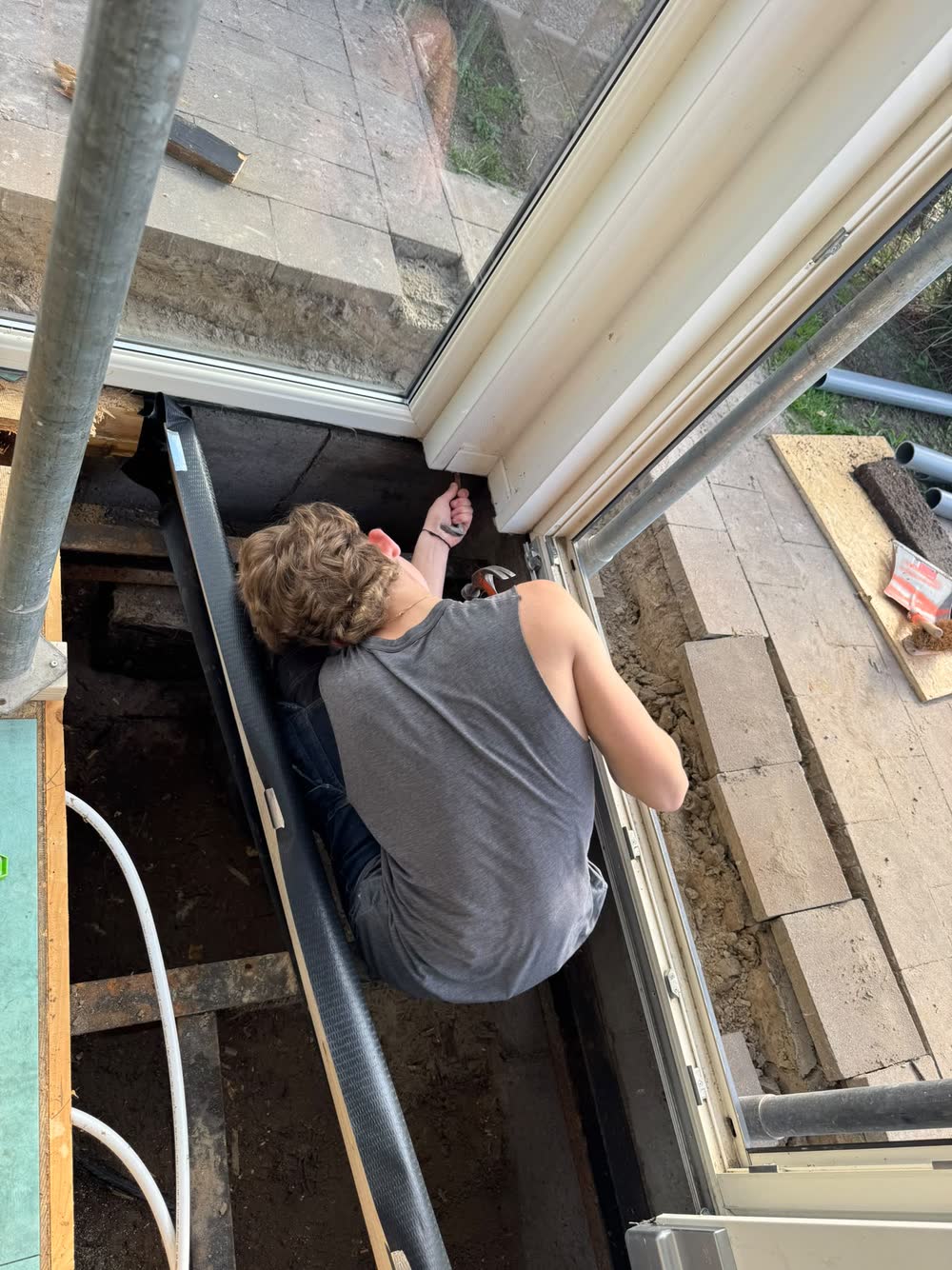 Een monteur werkt in de kruipruimte onder de schuifpui aan de nieuwe constructie