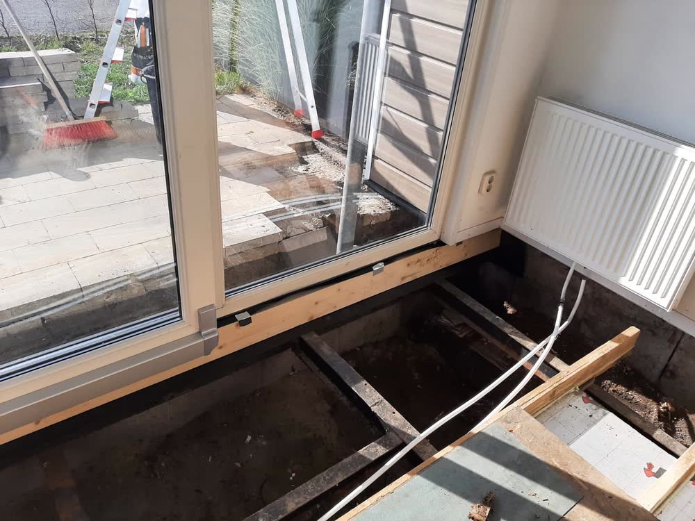 Een nieuwe houten balk onder de schuifpui, met folie ertussen tegen vocht