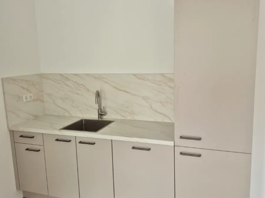 Compacte witte keuken met marmerlook achterwand
