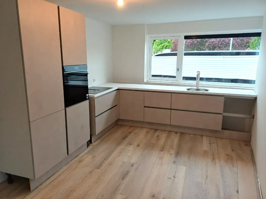 L-keuken met betonlook fronten en kastenwand