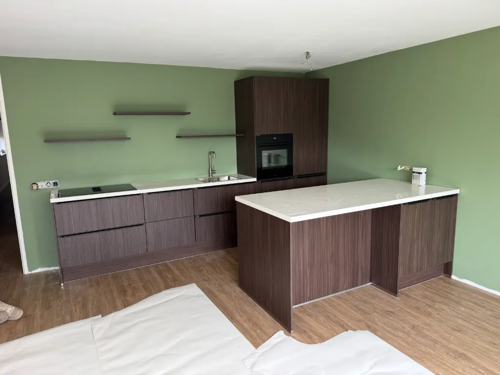 Notenhouten keuken met schiereiland voor een groene wand