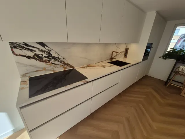 Witte greeploze keuken met marmerlook werkblad en achterwand